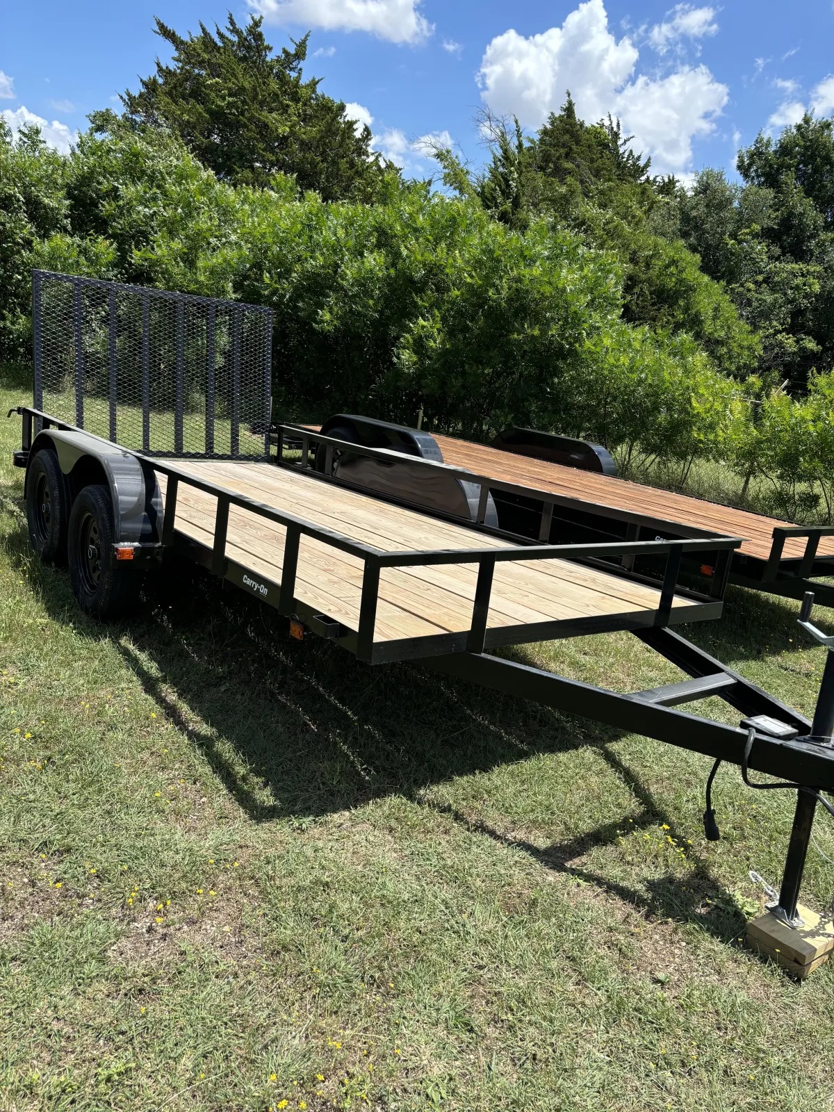 Black utility trailer with wooden deck and side rails